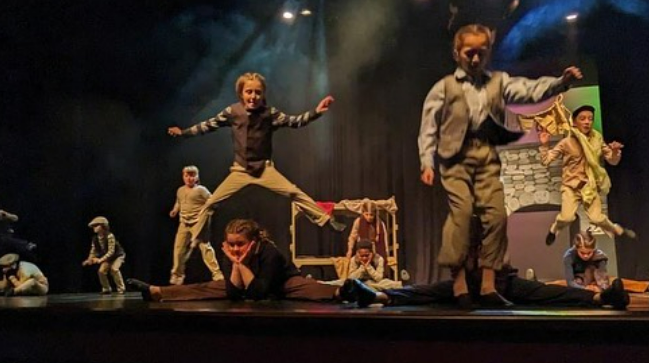 The student cast of Oliver Jr in action, jumping over one another on stage